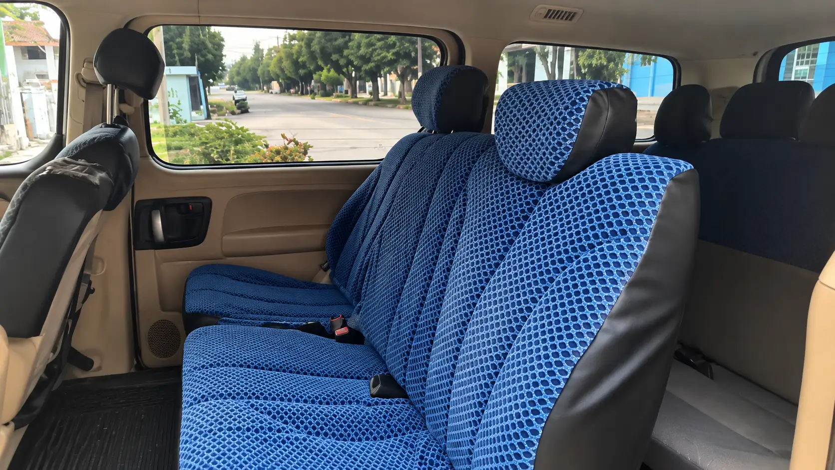 Tres asientos azules para pasajeros en el interior del vehículo.