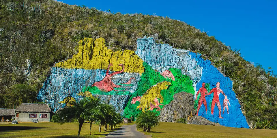 Paisaje con un mural de colores sobre una ladera rocosa.